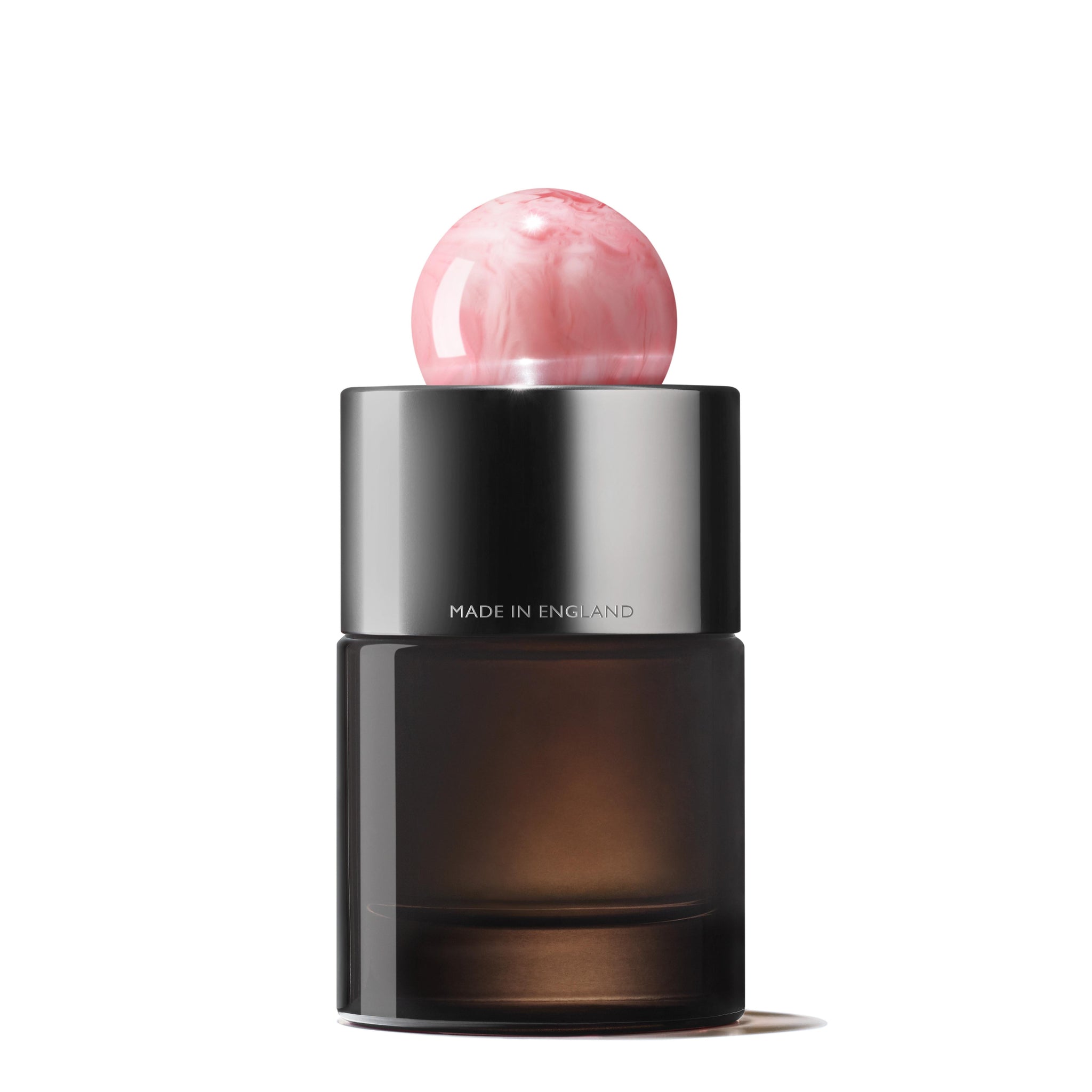 A dark glass bottle of Delicious Rhubarb & Rose Eau de Parfum 100ml with a metallic silver band and pink marble-like round cap. "MADE IN ENGLAND" is etched on the silver. Shot on a plain white background—perfect for peony fragrance lovers.